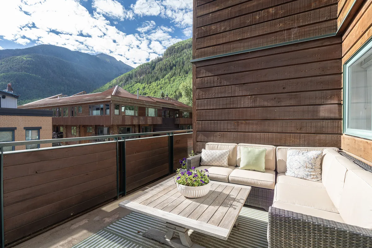 This image showcases a tranquil outdoor seating area with a beautiful mountain view and a vibrant flower pot, inviting relaxation and connection to Telluride's stunning natural surroundings. The arrangement encourages socializing or unwinding after a busy festival day.